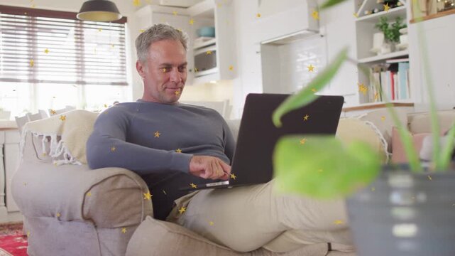 Mature man typing on laptop on sofa, viewing media, stars appearing as face shifting to laughter