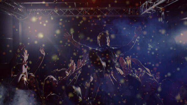 Artist leaning into crowd, causing lifting and passing him under concert lights, confetti drifting