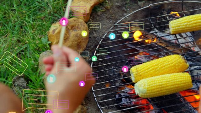 Hands reaching, turning skewers on grill for even cooking, lifting hot dog with AR bubbles floating