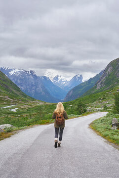 Mountain, backpacking and woman on road for adventure, mockup space and fresh air on journey or travel. Outdoor, person and hiking on weekend, exploration and trekking with view of valley and scenery
