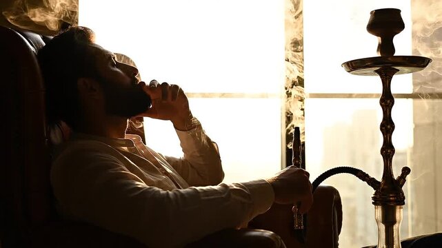 Man relaxing and smoking hooka in a luxurious backlit lounge