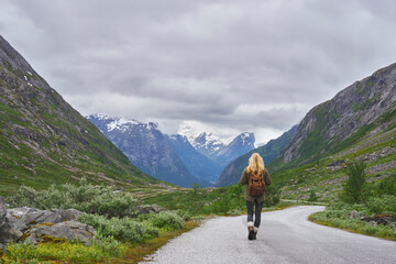 Fototapeta premium Mountain, trekking and woman on road for adventure, mockup space and fresh air on journey or travel. Outdoor, person and hiking on weekend, exploration and backpacking with view of valley or scenery