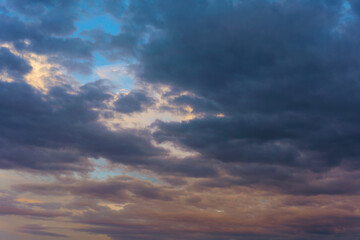 Fototapeta premium Dark clouds at sunset with a mix of blue, orange, and purple hues in the sky. 