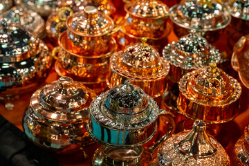 Fototapeta premium Metal coffee cezve with decorative oriental pattern on the shop window. Household items copper items for sale. Cupric coffeepots at the bazaar in Antalya Turkey. Turkish coffee pots. Metal coffee cezv