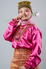 Naklejka premium Young Indonesian Asian Woman In Pink Traditional Costume With Hijab And Decorative Headpiece Holding A Rose And Smiling