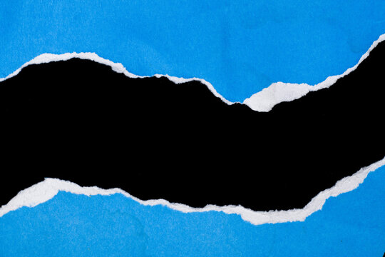 Torn paper reveals a stark black void against vivid blue. Edges fray unevenly, creating raw, textured contrast. Background hue shines bright, evoking boldness and depth. Perfect for design, editorial