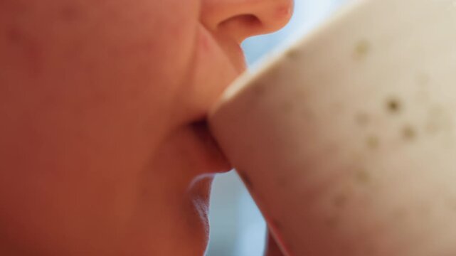 Closeup white woman sipping coffee cafe, ceramic cup at lips, soft morning bokeh, introspective pause between writing and reading, cozy natural light, relaxed expression, gentle exhale