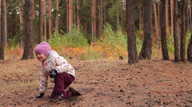 Little girl plays frisbee in autumn. Drops after throwing the cymbal.