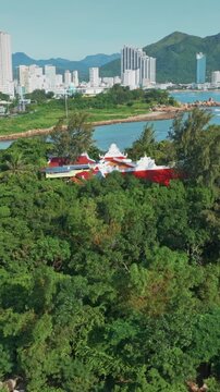 Vietnam's national flag and Buddhist flag fly on a lush green island of Chua Tu Ton overlooking the city of Nha Trang, Vietnam. The flags symbolize national pride and spiritual heritage