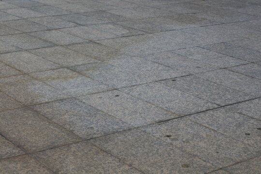 Textured granite paving stones create a seamless, repeating pattern on an outdoor surface