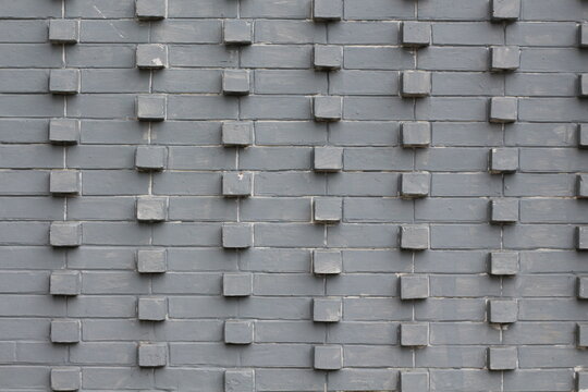 Textured gray brick wall with protruding square blocks in a repeating pattern