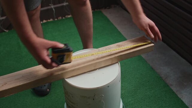 Man measuring wooden board with tape measure for precise marking creating process of material preparation and size control during construction and carpentry work