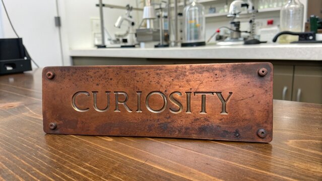 Engraved Copper Plate With the Word Curiosity Set in a Laboratory Environment
