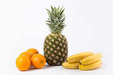 different fruits vitamine riched ripe whole pineapple oranges and bananas isolated on a white floor © Grumay