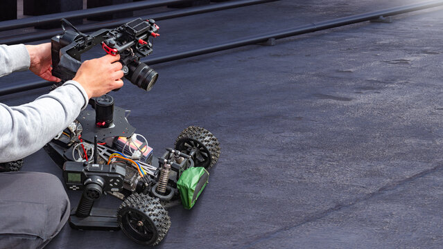 Robotics, Video production technology. Operator adjusts camera on RC car platform for low angle filming, mobile shooting and equipment setup