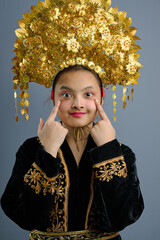 Naklejka premium Young Indonesian Asian Girl Wearing Ornate Gold Traditional Headdress and Embroidered Costume Portrait