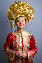 Naklejka premium Young Indonesian Asian Woman Wearing Traditional Gold Headdress and Embroidered Red Costume Smiling