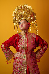 Naklejka premium Young Indonesian Asian Woman Wearing Ornate Gold Headdress and Red Traditional Costume Portrait for Cultural Celebration