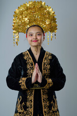 Naklejka premium Portrait Of A Young Indonesian Asian Woman Wearing A Gold Traditional Headdress And Embroidered Black Costume