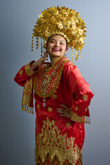Naklejka premium Young Indonesian Asian Woman in Red and Gold Traditional Costume With Ornate Gold Headdress Portrait