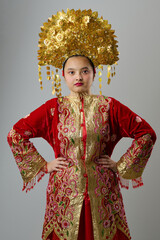 Naklejka premium Young Indonesian Asian Woman in Red and Gold Traditional Ceremonial Costume With Ornate Gold Headdress