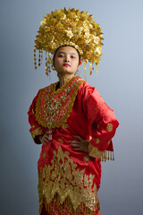 Naklejka premium Portrait Of Indonesian Asian Woman In Red Traditional Costume With Ornate Gold Headdress And Embroidery