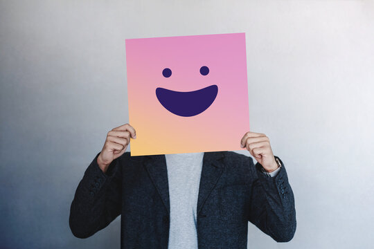 Person hiding face with smile mask, mental health concept, Fake happiness