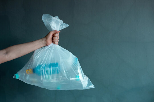 Hand holding plastic waste bag filled with bottles, Recycling and waste management