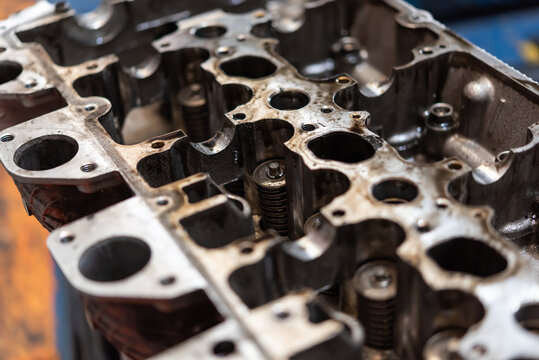 Detailed closeup of engine cylinder head showing ports valves and metal surfaces highlighting automotive repair maintenance and precision engineering components