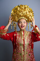 Naklejka premium Young Indonesian Asian Woman Wearing Traditional Gold Headdress and Red Embroidered Costume for Cultural Celebration