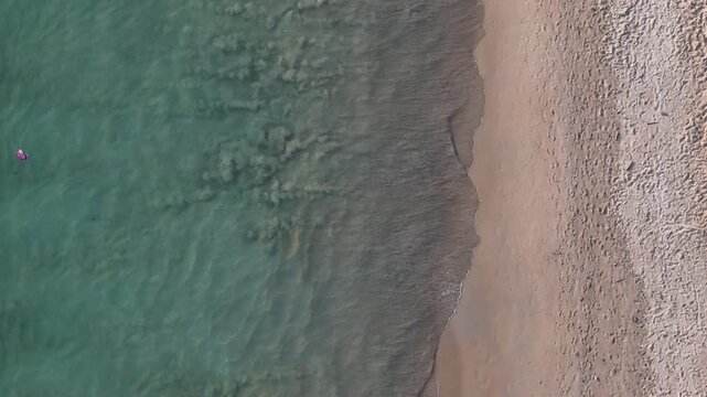 Aerial View of Serene Beach with Gentle Waves and Turquoise Water Lapping Against Sandy Shore Creating Peaceful and Inviting Atmosphere