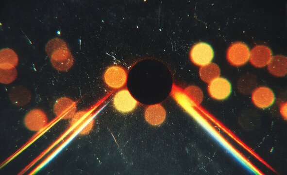 Dark circle obscuring bright, blurred lights and light streaks