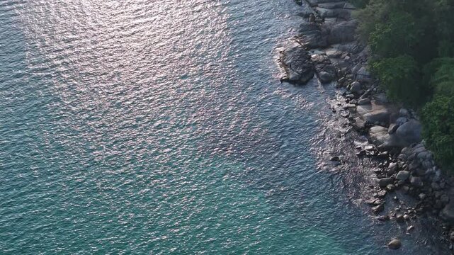Aerial View of Rocky Coastline with Shimmering Blue Sea and Lush Greenery Creating Serene and Picturesque Landscape