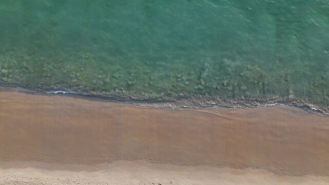 Aerial View of Serene Beach with Gentle Waves Lapping at Sandy Shoreline, Showcasing Tranquil Beauty of Sea and Sand