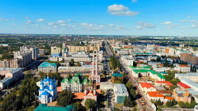 Tambov, Russia. The 107-meter Neoclassical belfry of the Kazan Monastery, its five-tiered campanile and gilded domes rising above the city grid under a clear summer sky, Drone footage