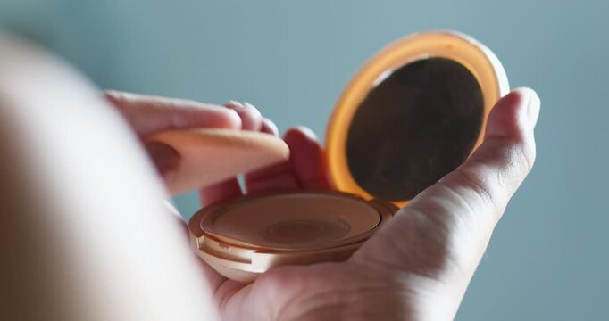 Woman applying powder with a puff from a compact case, soft lighting, beauty and skincare routine concept, minimal and elegant daily makeup moment, Close-up