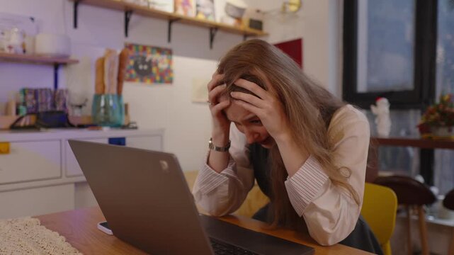 Young businesswoman feeling overwhelmed and frustrated while working remotely on her laptop, expressing stress and desperation after receiving bad news or facing difficult problem