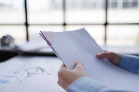 Business person holding documents reviewing report at office
