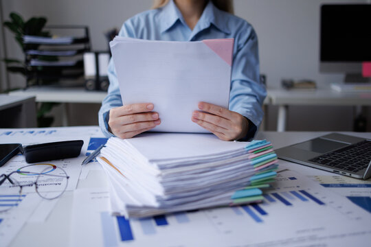 Businesswoman checking documents and managing paperwork on desk