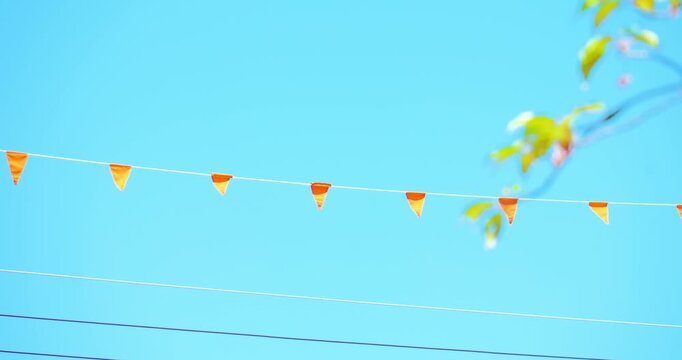Small orange pennant flags on wire under bright blue sky, copy space