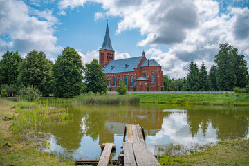 Obraz premium Scenic View of Olkovichi Church across Pond with Wooden Pier, Rural Heritage with copy space