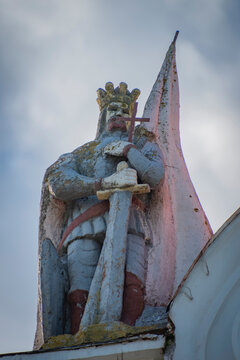 ncient Stone Knight Statue with Sword and Cross, Weathered Religious Sculpture in Soly with Copy Space