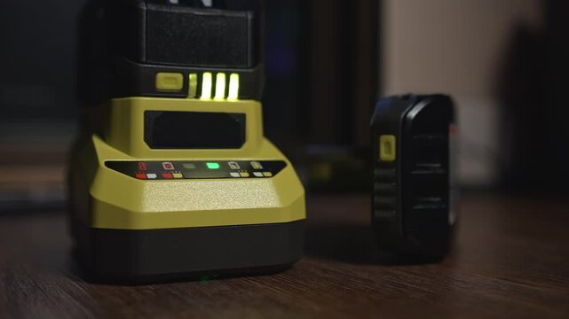 Power tool charger with battery and charge indicators on work surface shows charging process power stability and equipment readiness for operation
