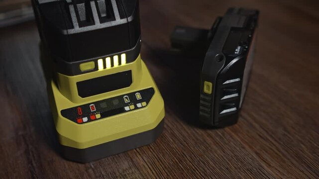 Power tool charger with battery and light level indicators on floor demonstrates charging process battery status control and tool preparation for further work