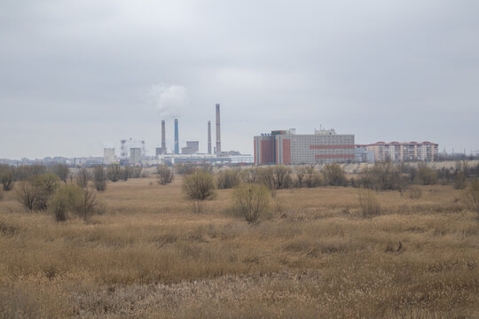 Industrial cityscape of Bucharest featuring a power plant with smoking chimneys and cooling towers viewed from the Vacaresti Nature Park wetlands
