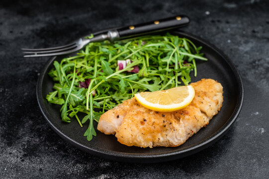 Healthy seafood meal with fried snapper fillet and green salad. Balanced dinner plate.