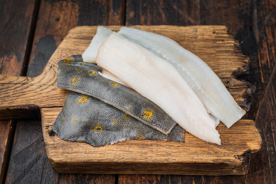 Fresh plaice flatfish fillets on wooden board with spices raw seafood ingredient on rustic background