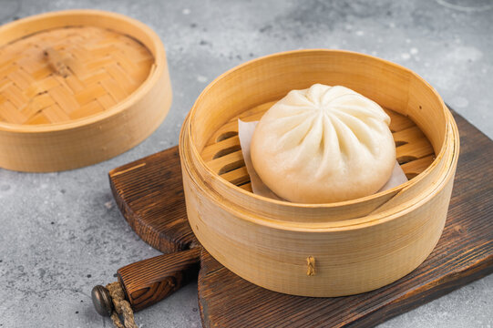 Nikuman steamed bun served in bamboo steamer, fluffy Asian dumpling with soft dough on light background with copy space