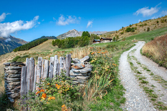 old and rustic  fence of  alpine garden between stone pilled in mountain along a trail crossing the countryside under blue sky