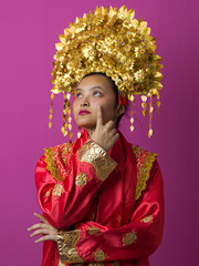 Naklejka premium Young Indonesian Asian Woman Wearing Traditional Gold Headdress And Red Embroidered Costume Portrait For Celebration